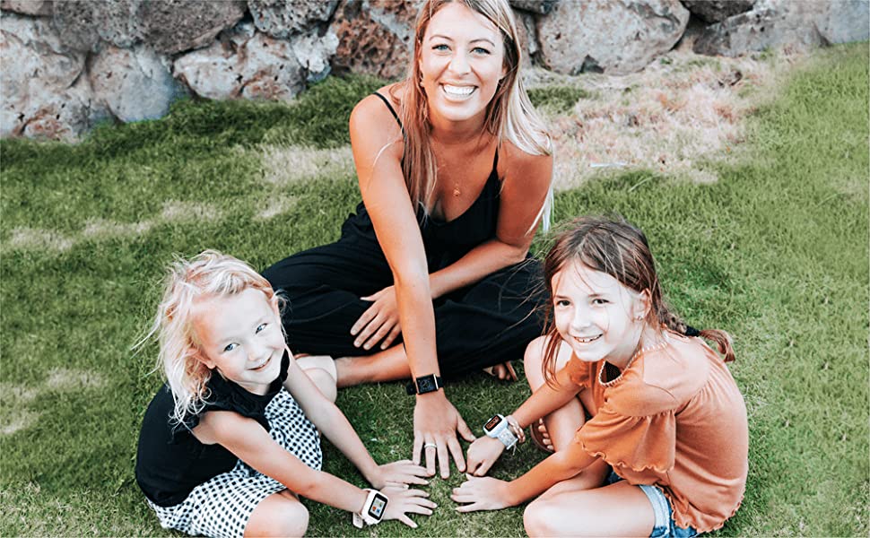 Photo of woman and two children smiling on the lawn and wearing iTouch watches.