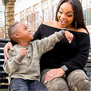 Photo of little boy showing his mom his watch while she smiles.