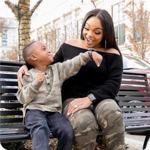 Photo of little boy showing his mom his watch while she smiles.